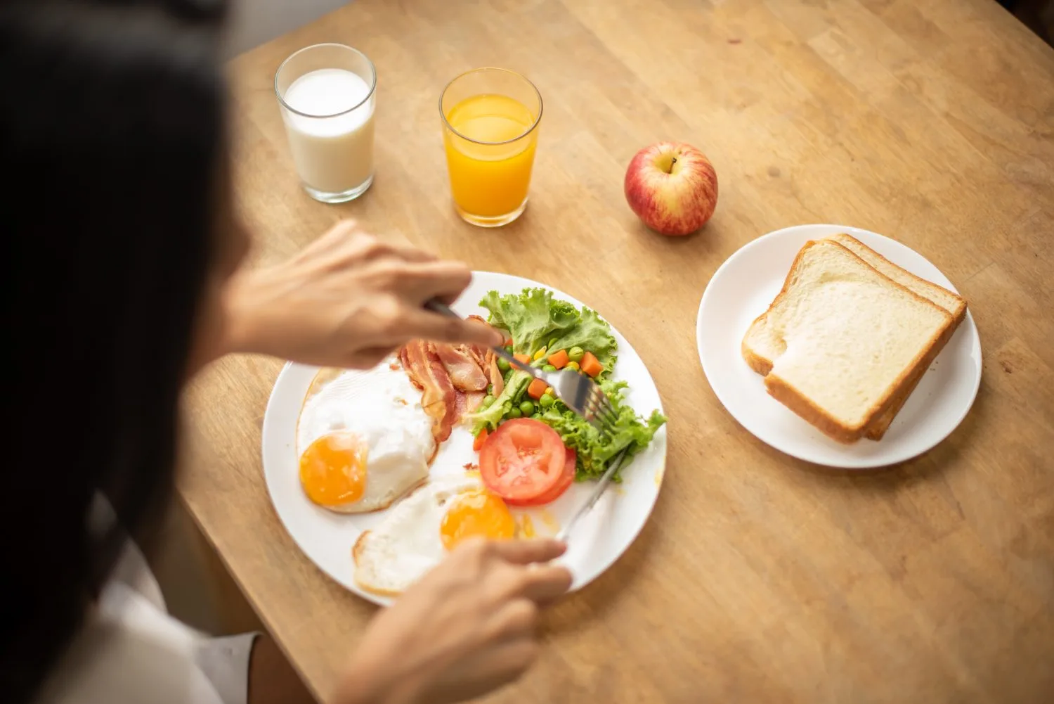 Breakfast table with fried eggs bacon freshly baked bread apple