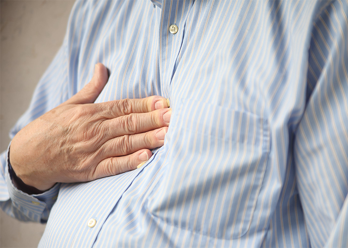 senior man with a hand on his chest experiencing heartburn 